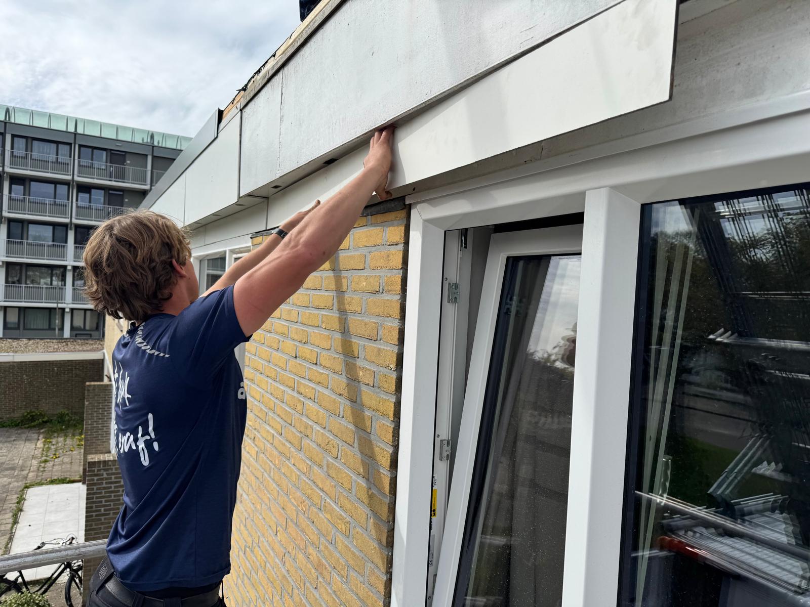 AddRoof vakman plaatst dakrandafwerking op een flatgebouw in Friesland